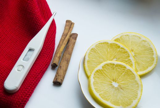 The concept of treating colds - lemon, cinnamon, thermometer scarf.