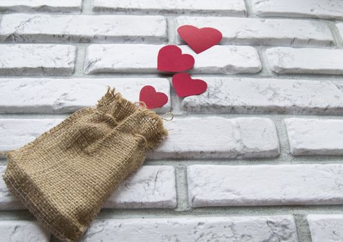 Valentine's day, red hearts canvas bag, background white brick wall.