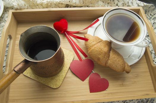 Valentine's day Breakfast croissant and coffee is served in a tray with heart.