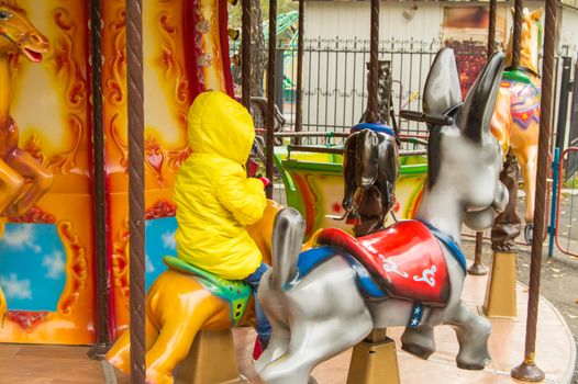 Children ride on the horses on the colorful carousel in the Park.