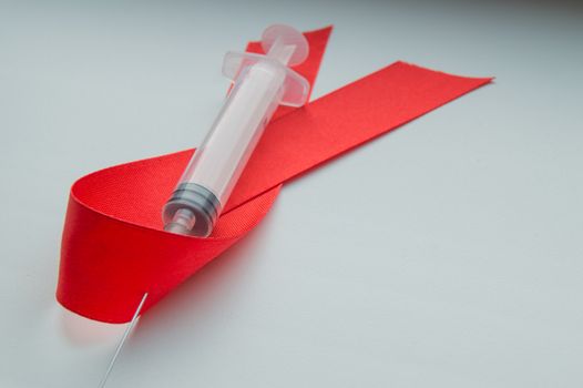 Awareness red ribbon and syringe on white background: world day against AIDS, the promotion of public support for the health of people living with HIV in December