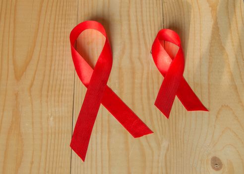 Awareness red ribbon on wood background: world day fight against AIDS, promotions to public support for the health of people living with HIV in December.