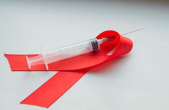 Awareness red ribbon and syringe on white background: world day against AIDS, the promotion of public support for the health of people living with HIV in December