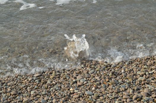 Sea wave on the shore of a pebble beach, water, foam, background.