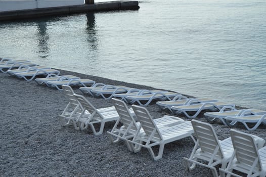 Empty sun loungers by the sea early in the morning, calm, sunrise.