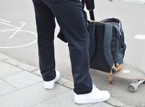 Skateboarder puts things in his backpack with the skateboard. The concept of sports lifestyle.