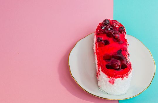 One beautiful cake with red icing lingonberries on a white plate, pink and blue pastel top view, copy space.