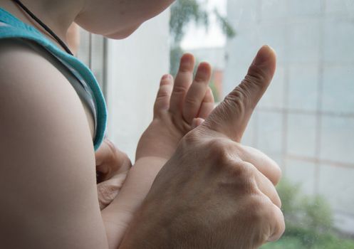 concept of a happy family - an adult holds the hand of a baby.