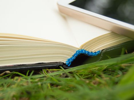 Books, smartphone on a green grass background, concept of education and training.