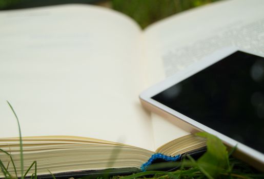 Books, smartphone on a green grass background, concept of education and training.