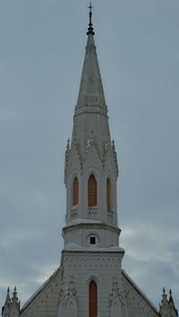 Old white bell tower of a protestant church against cloudy sky