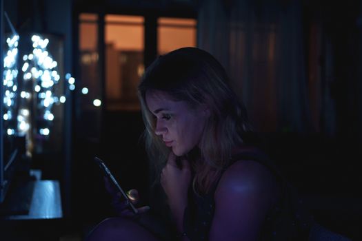 Girl using cellphone at night with neon light - pink and blue and black background