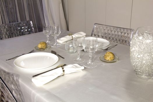 Dishes, cups, cutlery, napkins,candle, decor and bread served on the table with white tablecloth