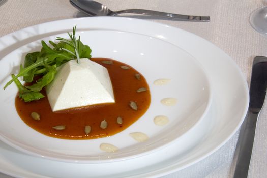 Pyramid made of pannacotta, sauce of red hot peppers, arugula and sunflower seeds
