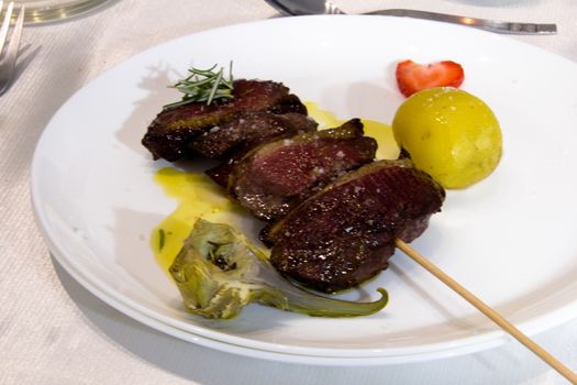 dish served with a duck magret skewer a patatoe and an artichoke