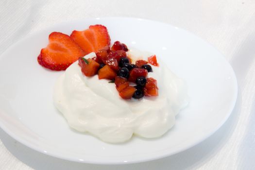 dish served with a pavlova dessert covered by strawberries and blueberries