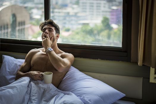 Young Handsome Shirtless Sleepy Man, Lying in Bed Yawning as He's Waking Up