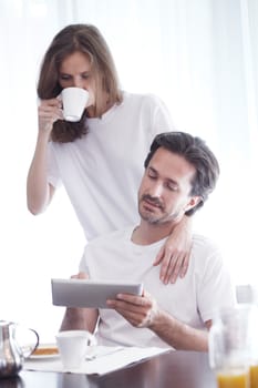 Couple having breakfast at home and using tablet