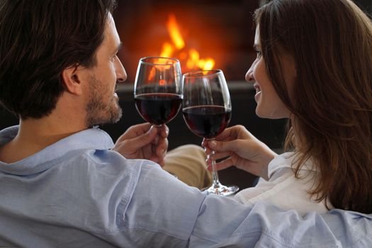 Romantic couple drinking wine at home near fireplace