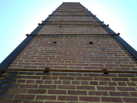 tall red brick chimney or masonry with metal support rods