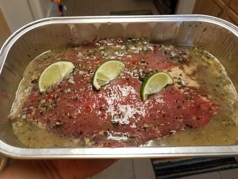 steak in marinade with sauce, garlic, limes, and seasoning