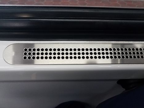 metal vent with holes near window on public train transportation with hexagon tiles