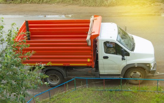 New red dump truck with white cab is empty, ready for transportation.