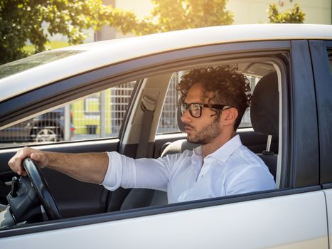 Handsome man sitting in his car, looking straight ahead and driving