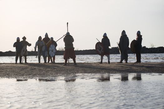 Slavic warriors reenactors with wearpons and shields training fighting outdoors at seaside