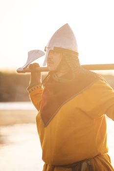 Portrait of slavic warrior reenactor with axe posing outdoors at seaside