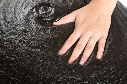 The female hand lies on black therapeutic mud