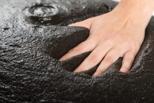 The female hand lies on black therapeutic mud