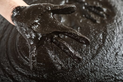 The female hand lies on black therapeutic mud