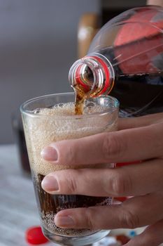 Pouring coke in the glass closeup. Bubbles in the glass