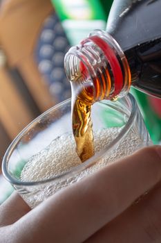 Pouring coke in the glass closeup. Bubbles in the glass