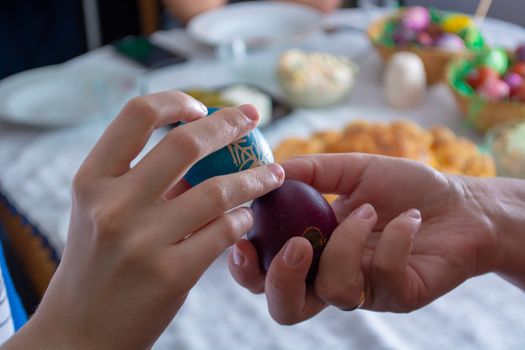 Knocking eggs on ortodox easter with table full of food in the background