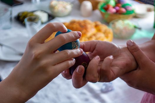 Knocking eggs on ortodox easter with table full of food in the background