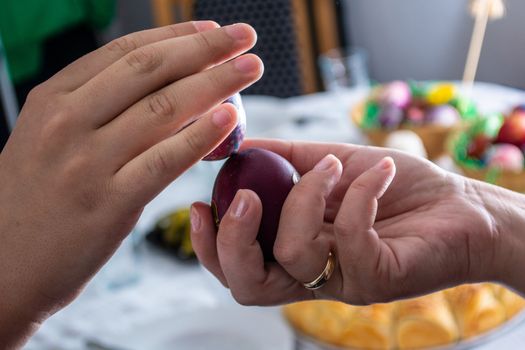 Knocking eggs on ortodox easter with table full of food in the background