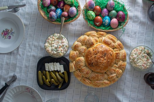 Table ful of food on easter holyday. Colored eggs and bread shoot from upper angle