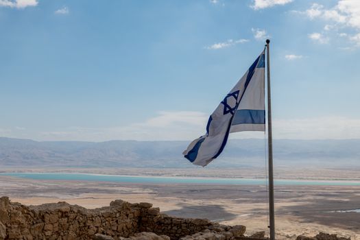 the israelian flag with the dead sea as background, seen from masada