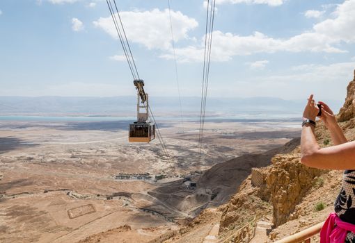woman making photo of the cable car going to masada in israel