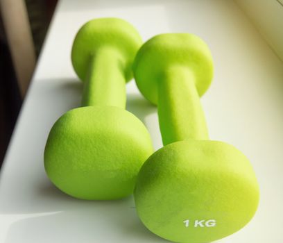 Concept of fitness, healthy lifestyle-two green dumbbells for sports, sunlight.