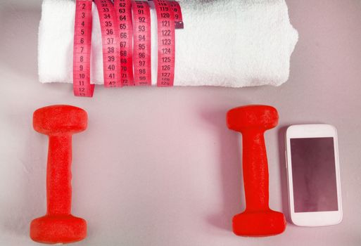 Fitness concept, dumbbell, mobile and a towel and measuring tape, top view.