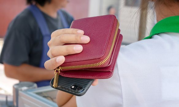 Woman holds Wallet and Smartphone over the Shoulder Unaware of the Danger of Purse Snatchers
