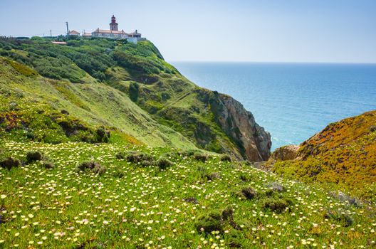 Lighthouse and wildflowers bloom at Cabo da Roda, Sintra, Portugal