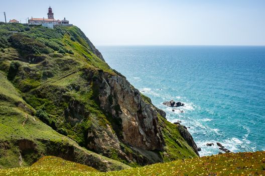 Lighthouse and wildflowers bloom at Cabo da Roda, Sintra, Portugal