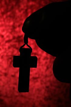 Silhouette of human praying to the GOD while holding a crucifix symbol