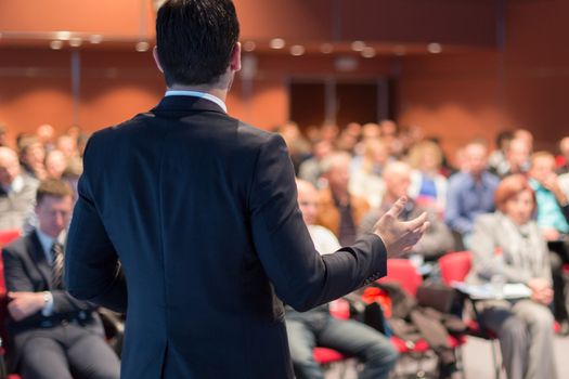 Speaker giving a talk on corporate business conference. Unrecognizable people in audience at conference hall. Business and Entrepreneurship event.