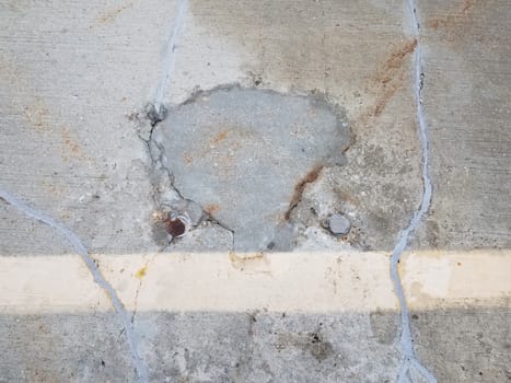 cracked and damaged and repaired grey cement in parking lot