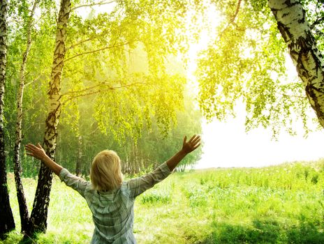 Summer, family, woman in the open in the forest near the trees raised her hands towards the sunlight, enjoying the summer heat and sun, concept of ecology and nature protection.